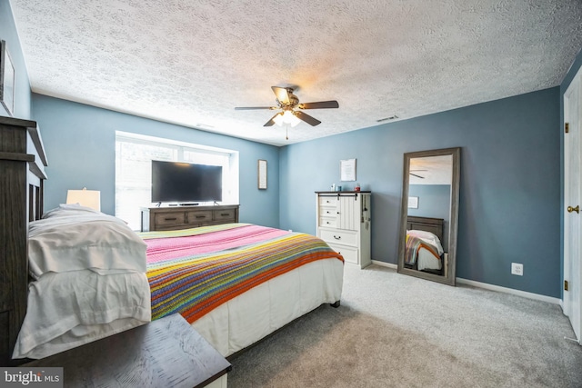 carpeted bedroom featuring ceiling fan, baseboards, visible vents, and a textured ceiling