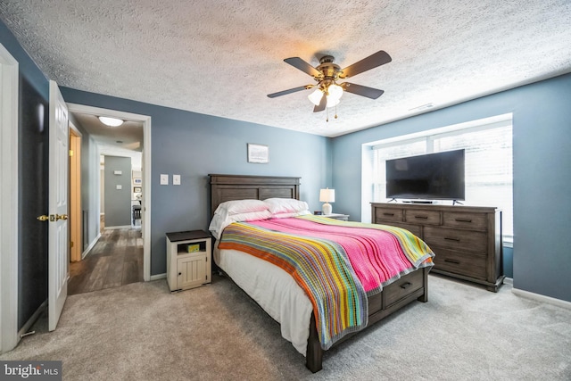 bedroom featuring baseboards, light carpet, and a textured ceiling