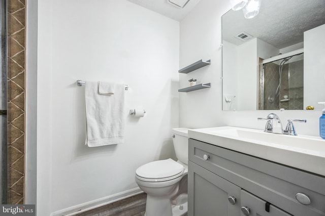 bathroom with visible vents, toilet, a textured ceiling, wood finished floors, and a shower stall