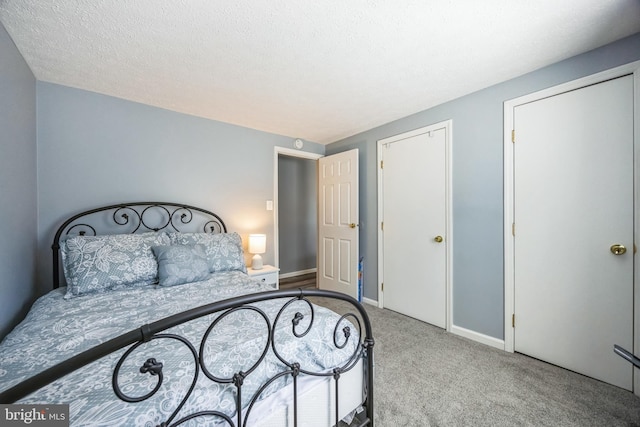 carpeted bedroom featuring baseboards and a textured ceiling