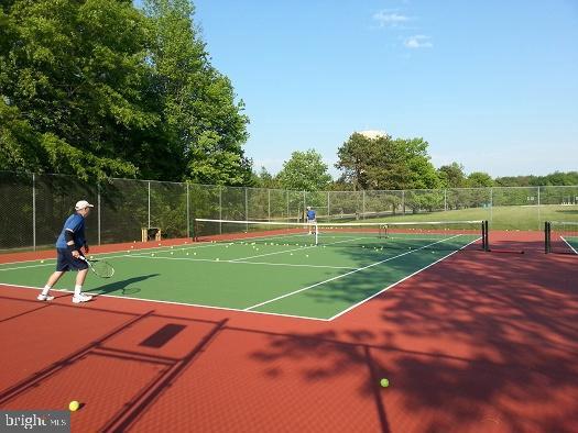 view of tennis court with community basketball court and fence