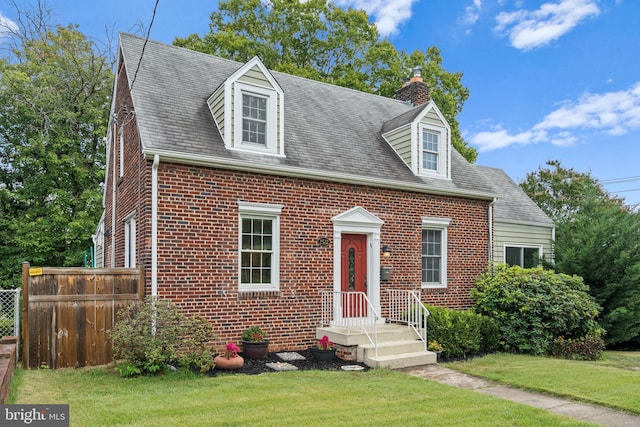 cape cod home featuring a front yard, brick siding, fence, and a chimney