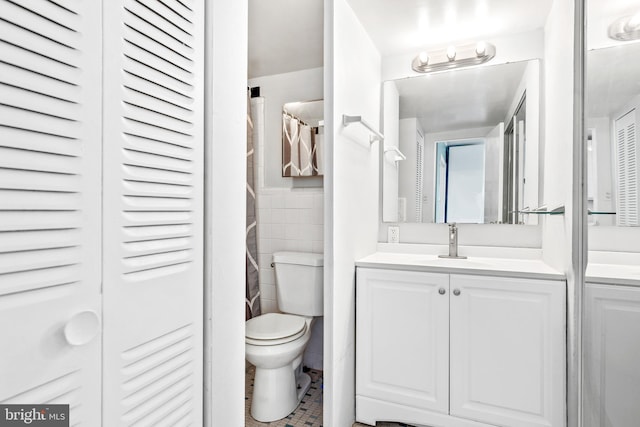 full bathroom with a closet, toilet, tile walls, and vanity