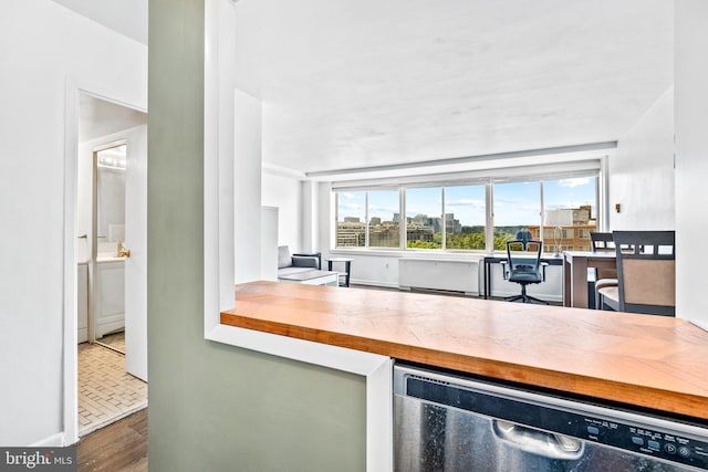 kitchen with wood finished floors, dishwashing machine, wooden counters, and a view of city