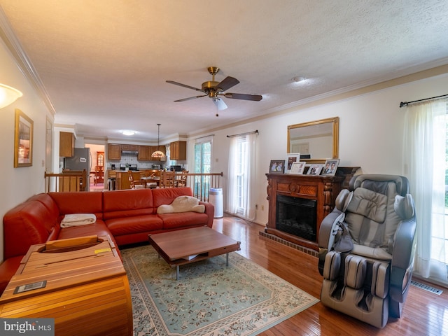 living area featuring a wealth of natural light, visible vents, wood finished floors, and ornamental molding