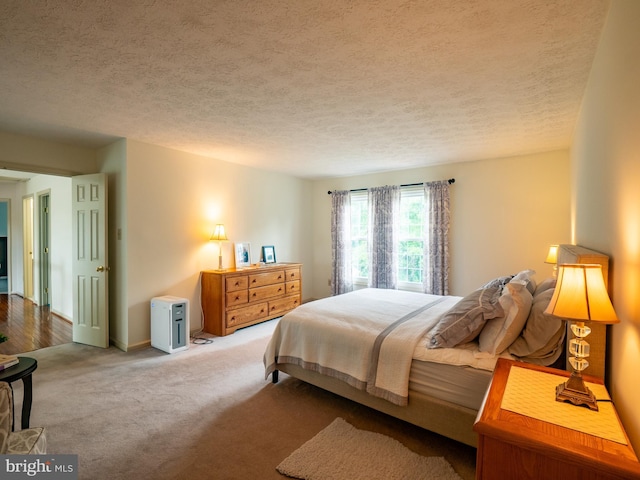 carpeted bedroom featuring a textured ceiling and baseboards