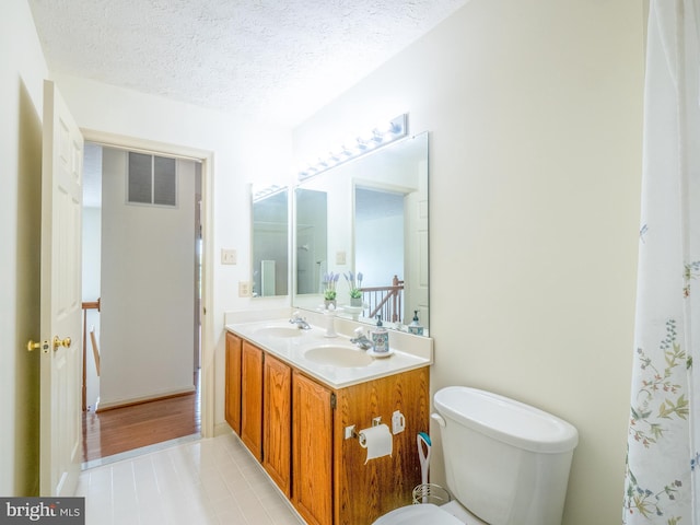 bathroom with toilet, a textured ceiling, visible vents, and a sink