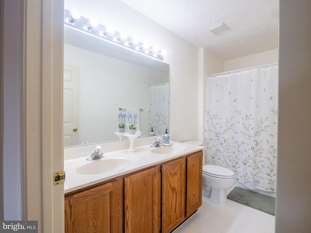 bathroom featuring a sink, a textured ceiling, toilet, and double vanity