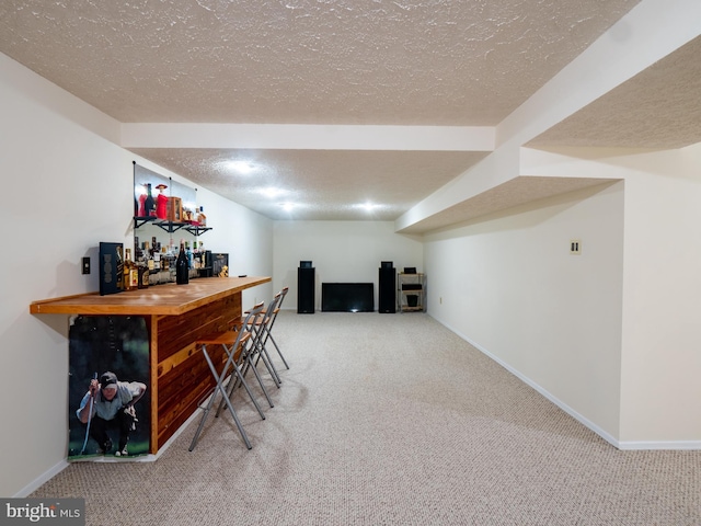 bar with a textured ceiling, a dry bar, carpet, and baseboards