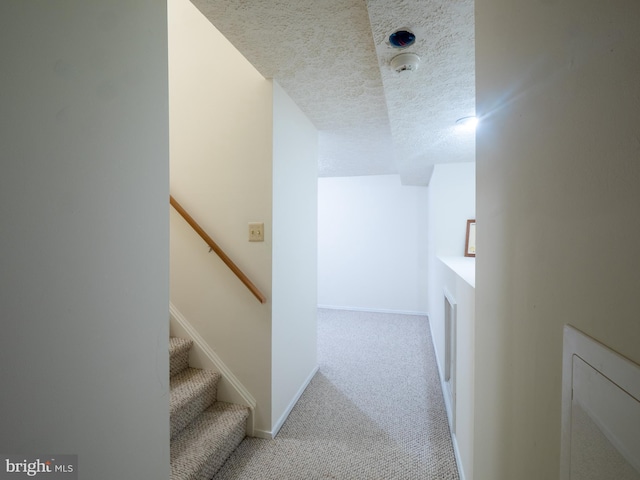 stairs featuring baseboards, a textured ceiling, and carpet flooring