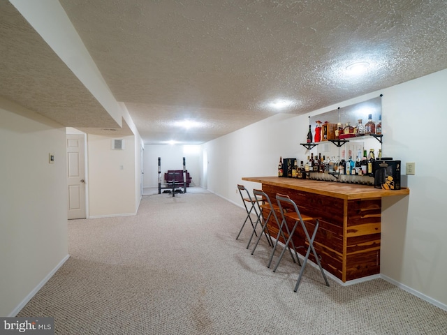 bar with a dry bar, baseboards, carpet floors, and a textured ceiling