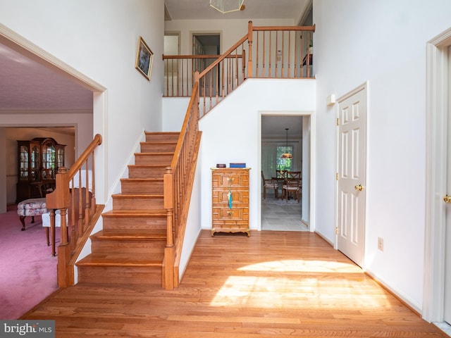 stairway featuring a towering ceiling, baseboards, and wood finished floors