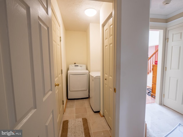 laundry room with a textured ceiling, laundry area, light tile patterned floors, and independent washer and dryer