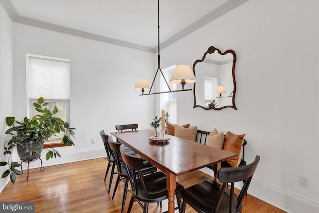 dining space featuring a chandelier, light wood-type flooring, crown molding, and baseboards