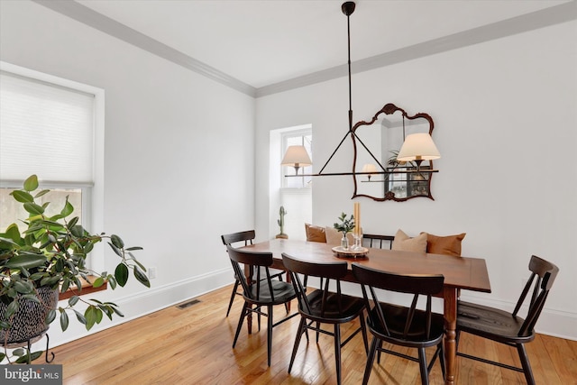 dining room with visible vents, an inviting chandelier, ornamental molding, wood finished floors, and baseboards