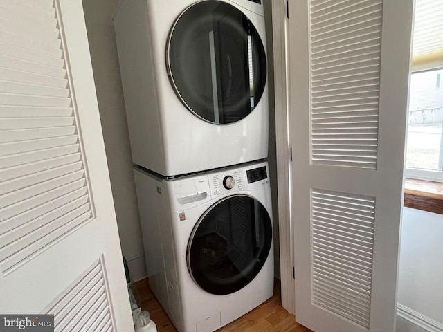 washroom with laundry area, stacked washer / drying machine, and wood finished floors