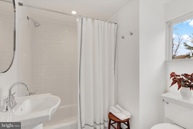 bathroom featuring shower / bath combo with shower curtain, a sink, and toilet