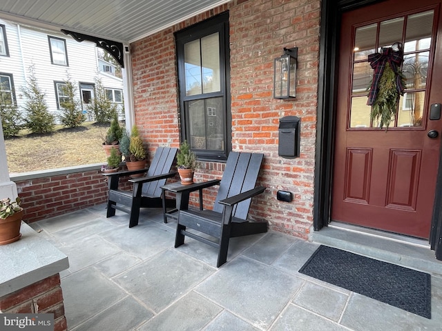 doorway to property with covered porch and brick siding