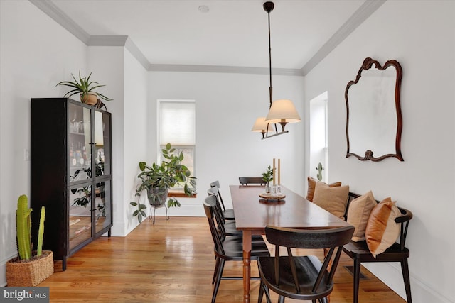 dining room with baseboards, crown molding, and light wood finished floors