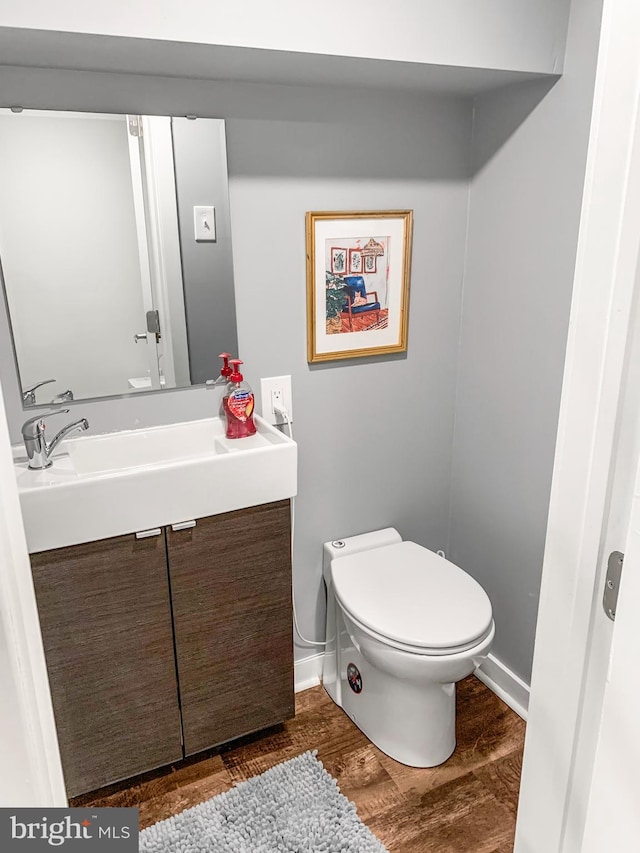 half bath featuring toilet, wood finished floors, and vanity