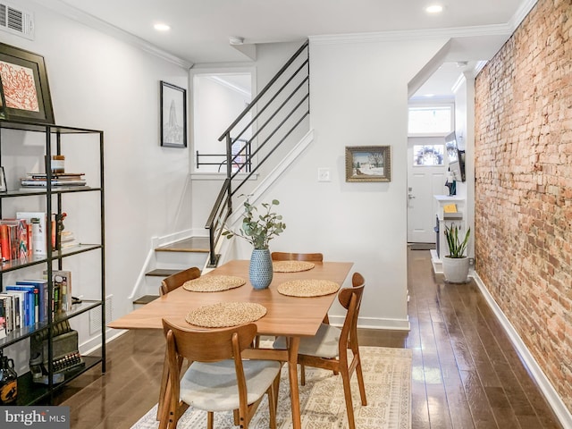 dining area with stairway, visible vents, brick wall, ornamental molding, and dark wood-type flooring