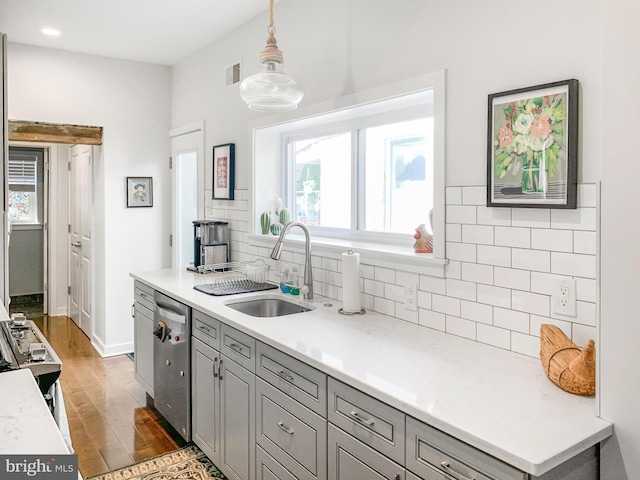 kitchen with visible vents, light wood-style flooring, gray cabinets, a sink, and decorative backsplash