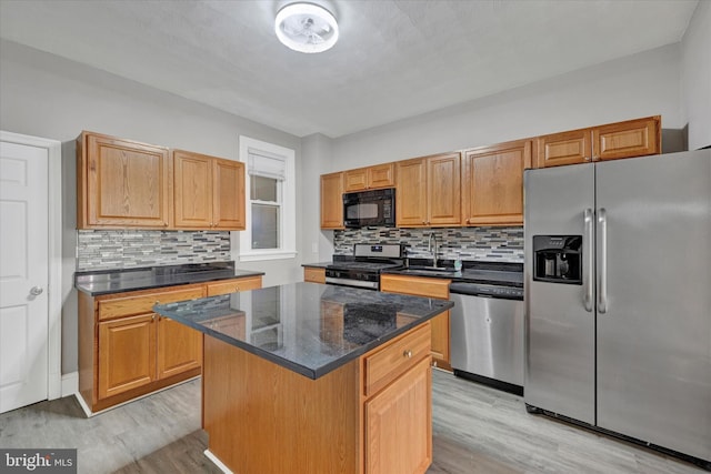 kitchen featuring stainless steel appliances, light wood-type flooring, a kitchen island, and decorative backsplash