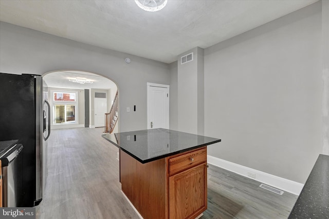 kitchen featuring appliances with stainless steel finishes, visible vents, arched walkways, and wood finished floors