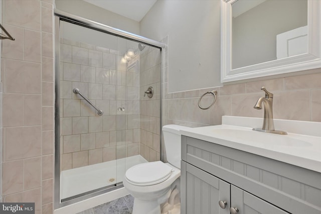 full bathroom with toilet, a wainscoted wall, vanity, tile walls, and a stall shower