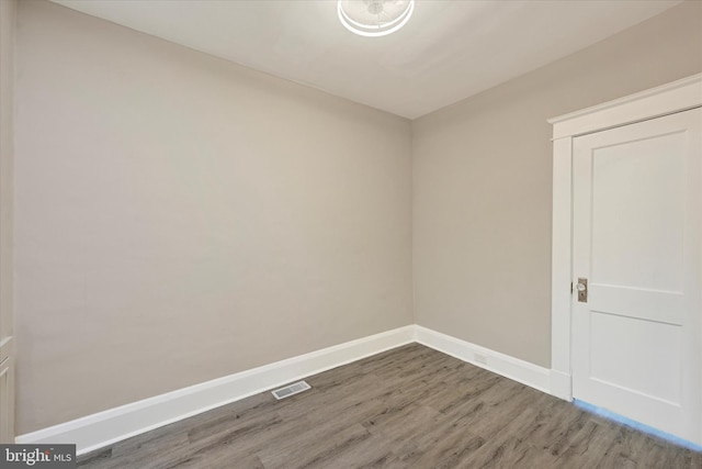 spare room with baseboards, visible vents, and wood finished floors