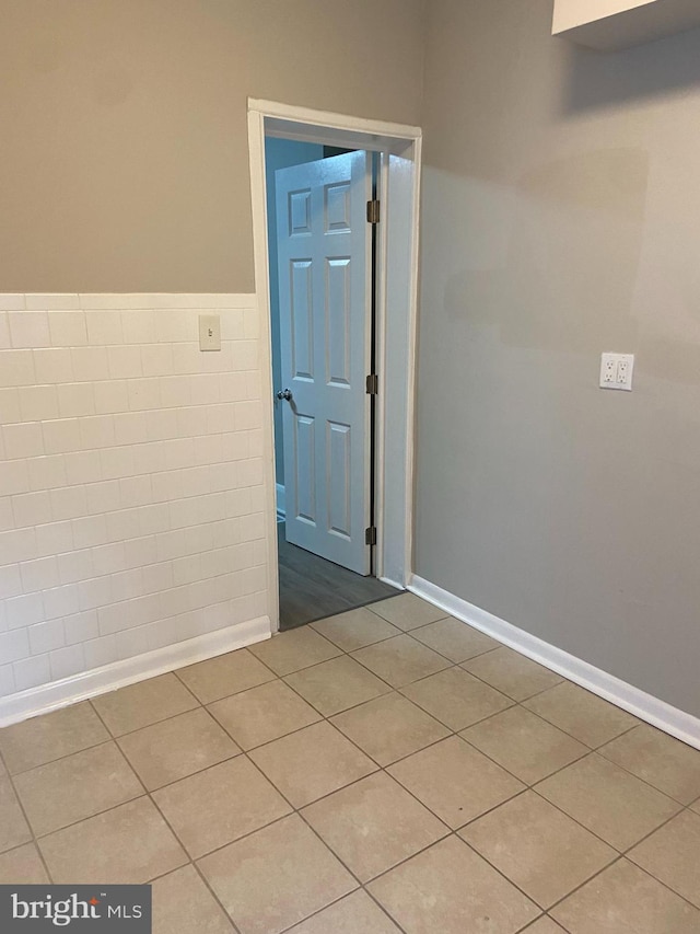 unfurnished room featuring tile patterned flooring and tile walls