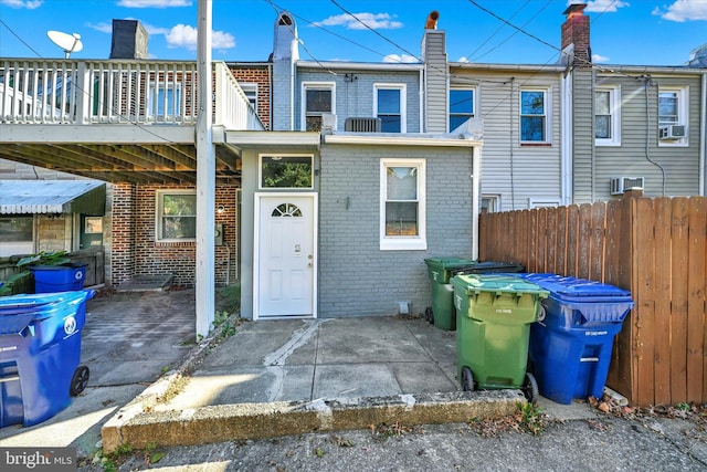 rear view of property with brick siding, cooling unit, and fence