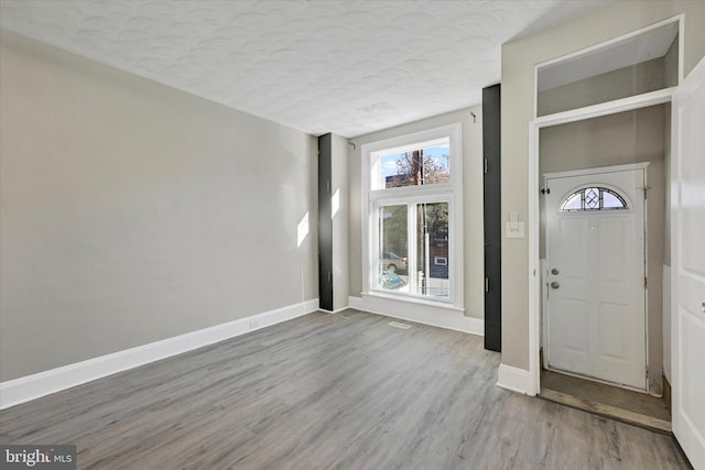 entryway with a textured ceiling, baseboards, and wood finished floors