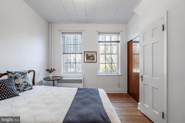 bedroom featuring baseboards, wood finished floors, and radiator