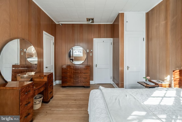 bedroom with wooden walls and light wood finished floors