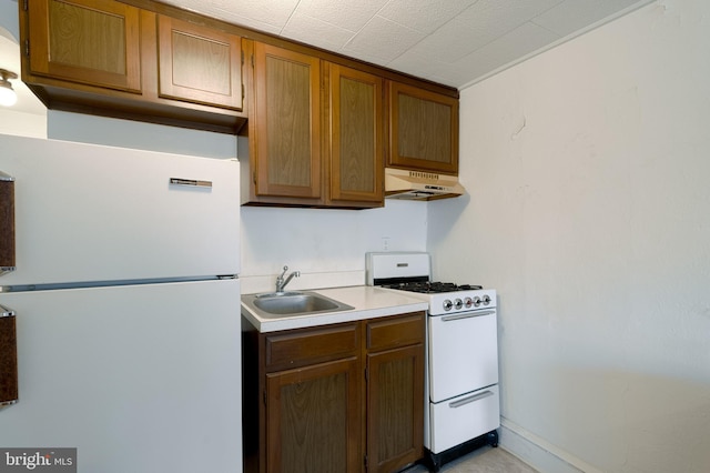 kitchen featuring under cabinet range hood, white appliances, a sink, light countertops, and brown cabinetry