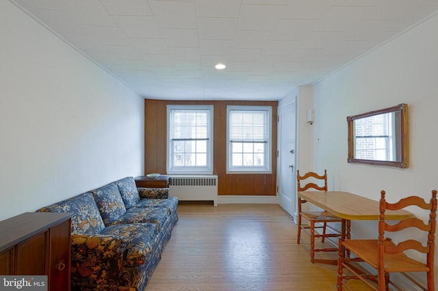 living area featuring baseboards, light wood-type flooring, and radiator