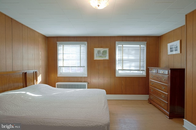 bedroom featuring baseboards, light wood finished floors, and radiator heating unit