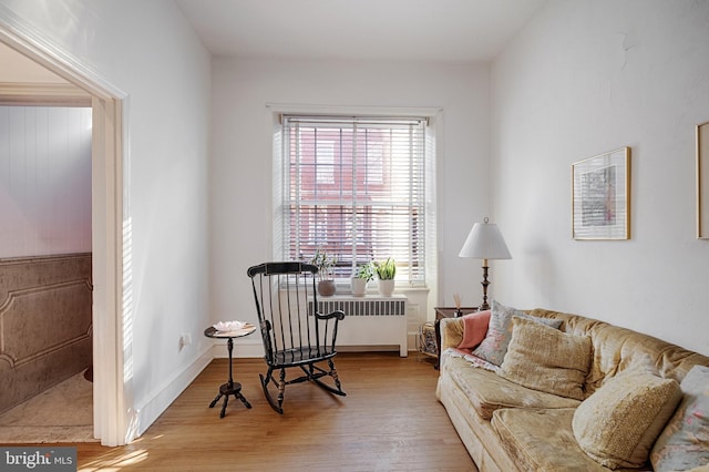 living area with baseboards, radiator heating unit, and wood finished floors