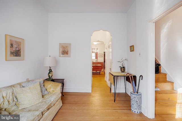 interior space featuring light wood-style flooring, a chandelier, stairway, and baseboards