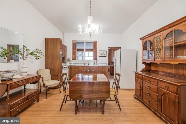 dining space featuring lofted ceiling, light wood-style flooring, and a chandelier