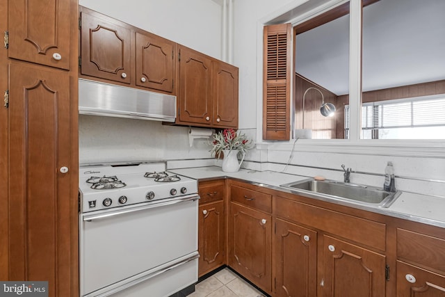 kitchen with light countertops, white range with gas cooktop, a sink, and under cabinet range hood