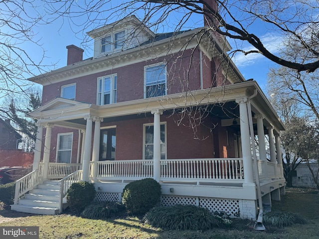 american foursquare style home with brick siding and covered porch