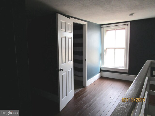 unfurnished bedroom with wood-type flooring, a textured ceiling, and baseboards