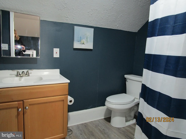 bathroom with toilet, vaulted ceiling, vanity, a textured ceiling, and wood finished floors