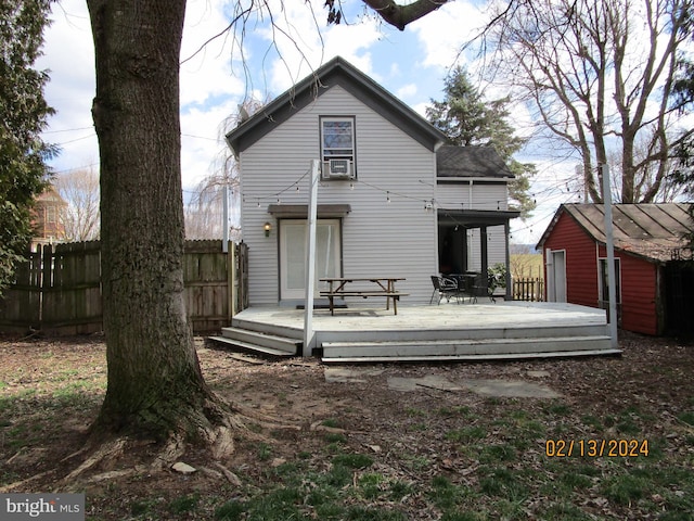 back of house featuring fence, a deck, and an outdoor structure