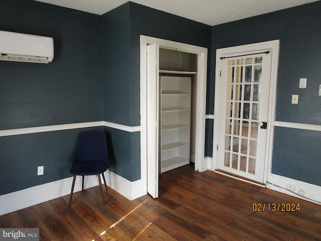 interior space with baseboards, wood finished floors, and a wall mounted air conditioner