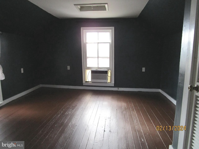 empty room with dark wood-type flooring, cooling unit, visible vents, and baseboards