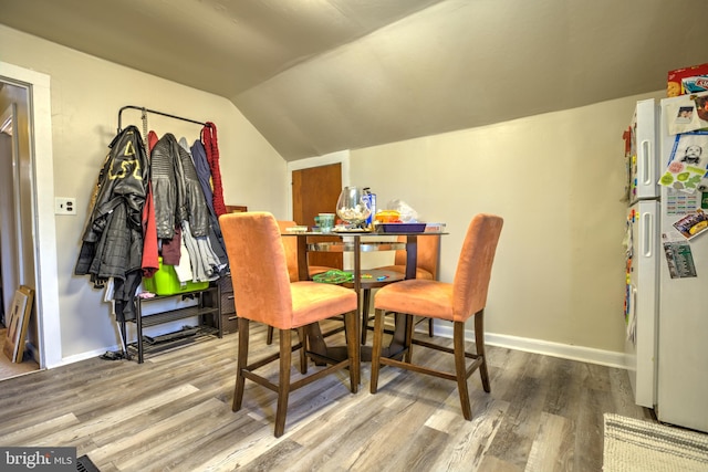 dining space with vaulted ceiling, wood finished floors, and baseboards