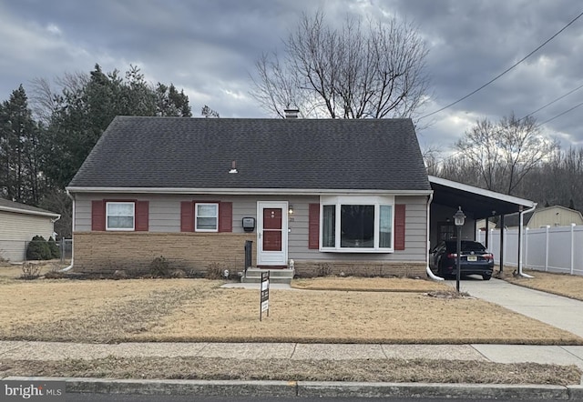 view of front of home featuring fence, roof with shingles, entry steps, concrete driveway, and a carport